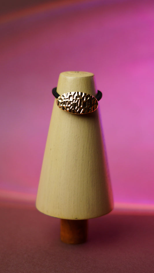 Gold hair tie on a wooden stand 